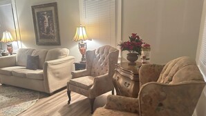 A living room with a sofa, armchairs, a coffee table, and a lamp.