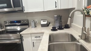 A modern kitchen with stainless steel appliances, a coffee maker, and a sink.