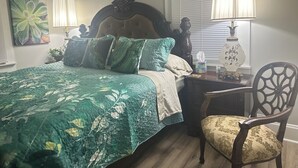 A bedroom with a bed, two bedside lamps, a chair, and a nightstand with a lamp.