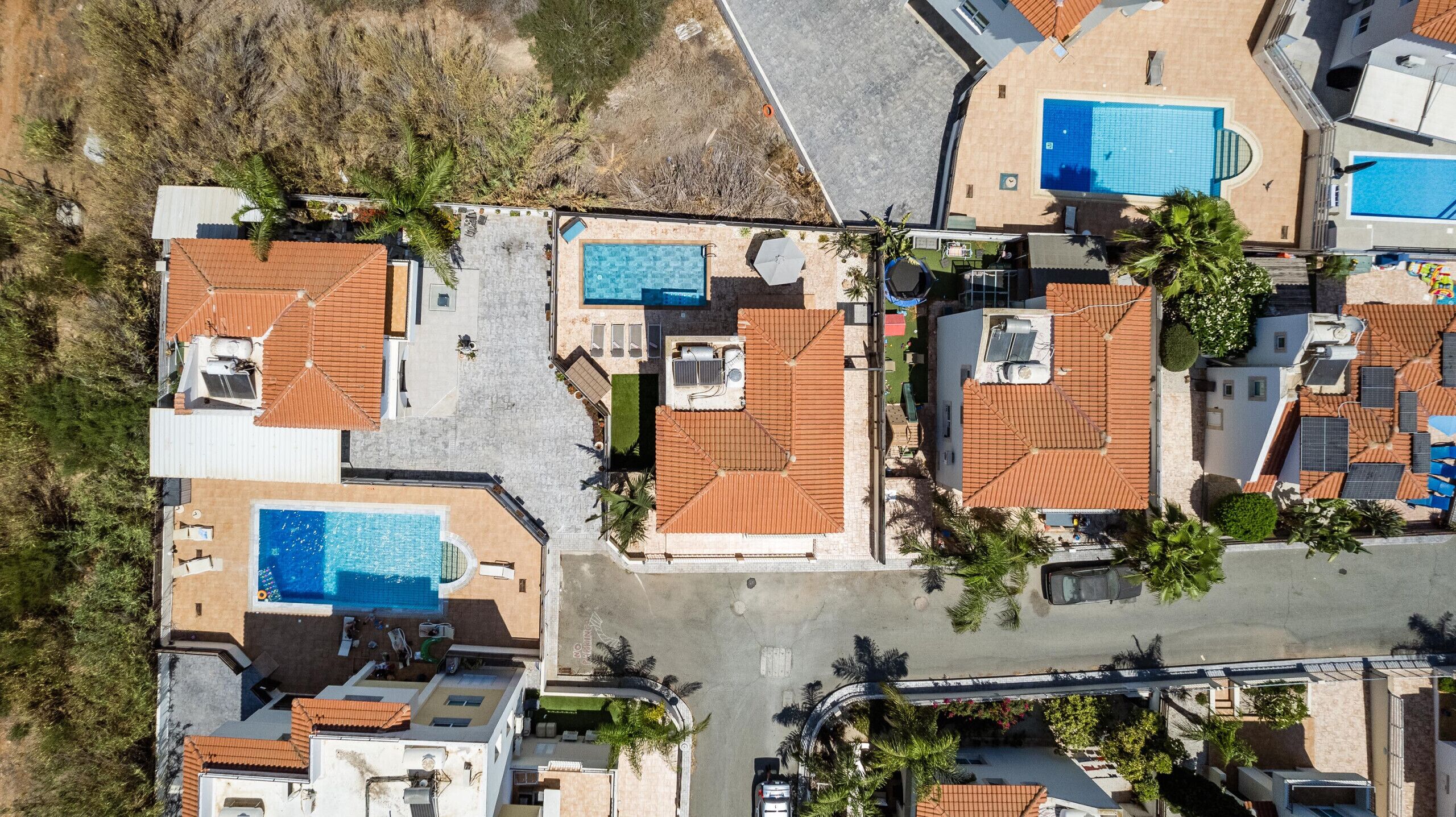 Vista aérea de una zona residencial con varias casas, cada una con piscina y tejado de baldosas.