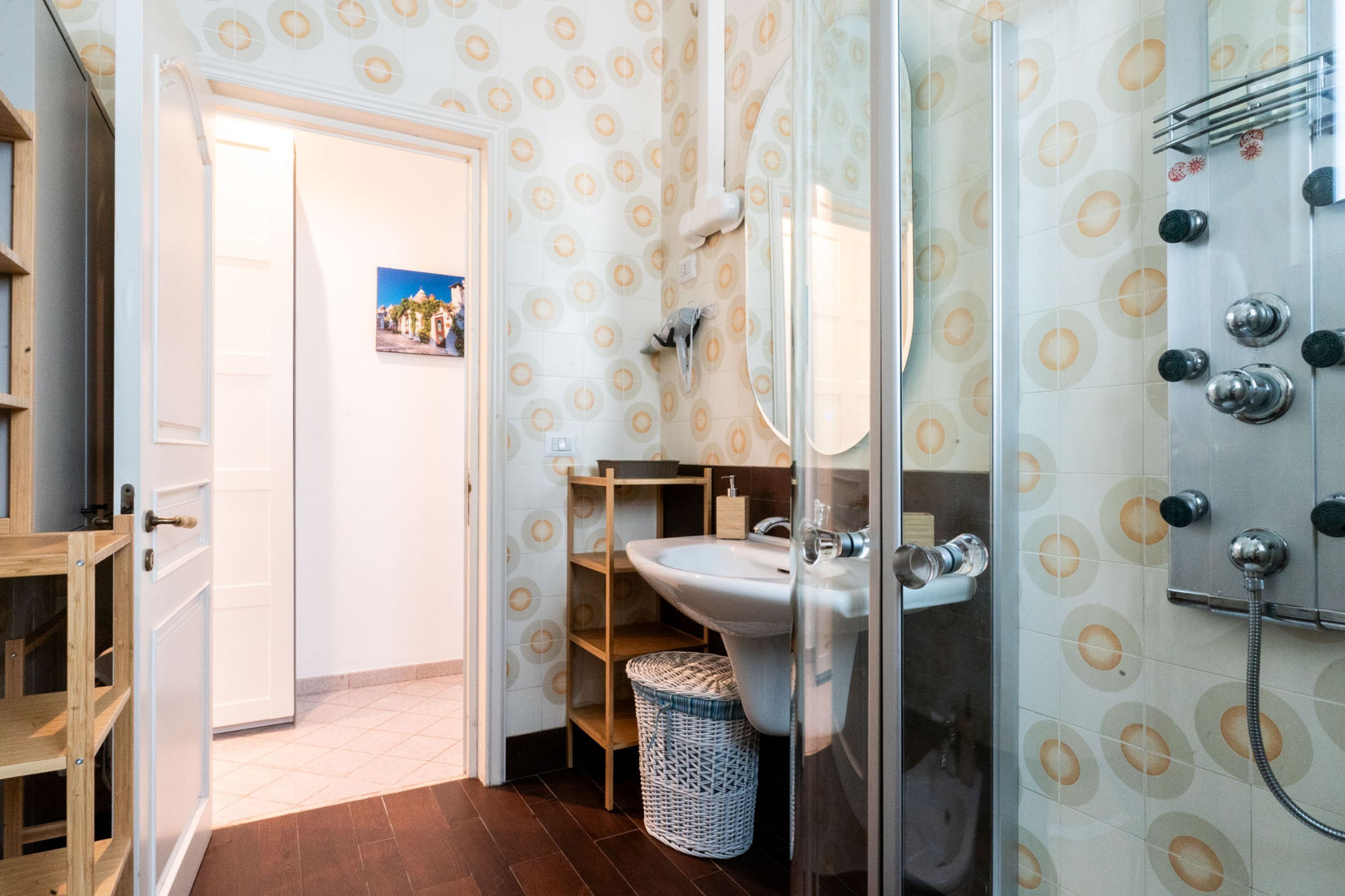 A bathroom with a shower, sink, and a small shelf with a basket.