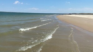 Ein Strand mit sanften Wellen und blauem Himmel.