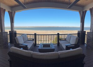 Un espace extérieur aménagé, abrité et doté de mobilier en osier, offrant une vue sur un lac.