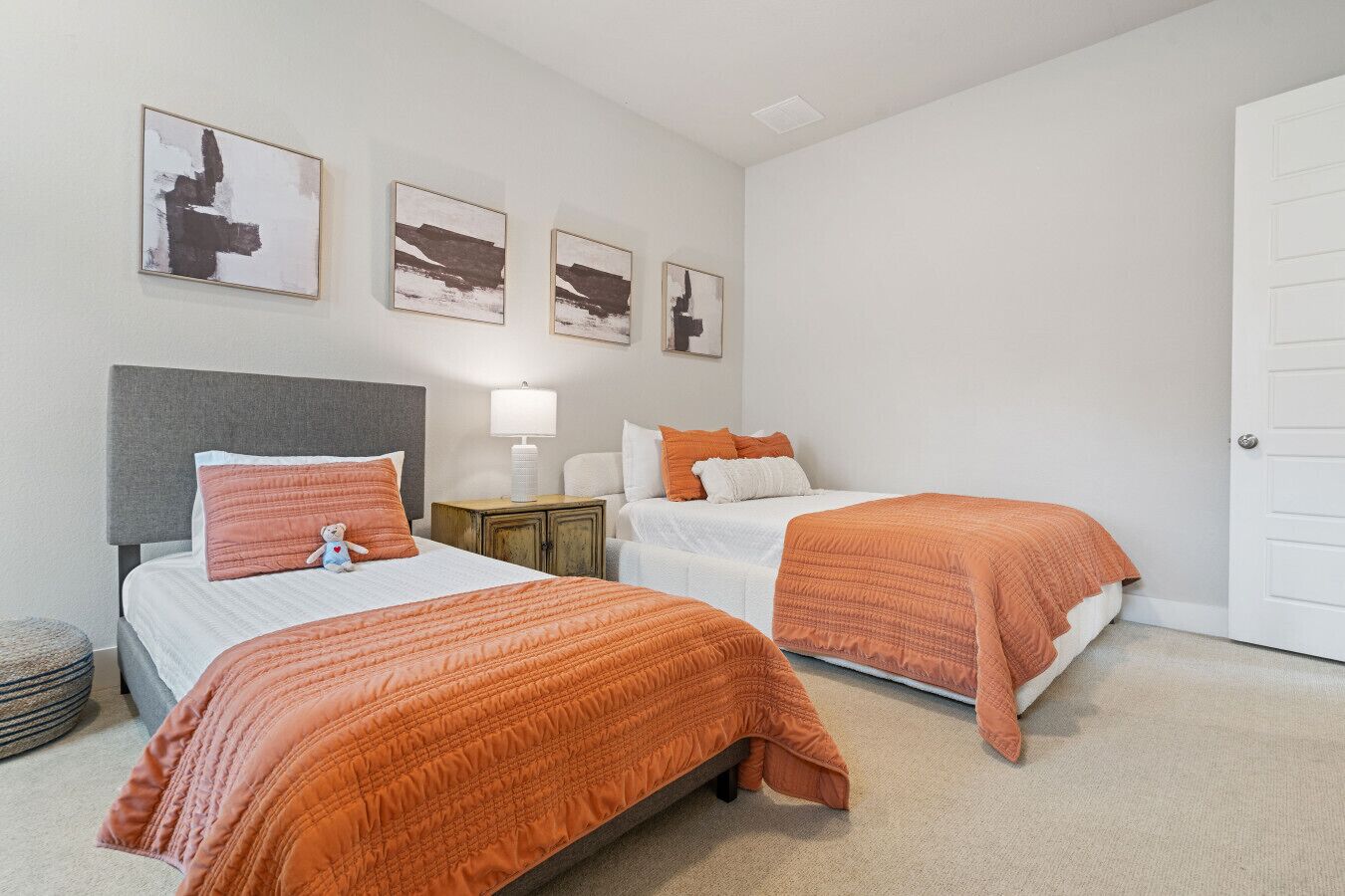 Una habitación de hotel con dos camas, una mesita de noche con lámpara y tres cuadros enmarcados en la pared.