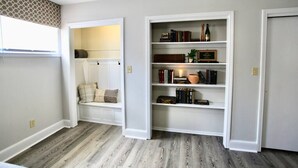 A room with a built-in bench, a bookshelf with books and decorative items, and a patterned wall. -  The Lounge - Downtown Chillicothe (Chillicothe)