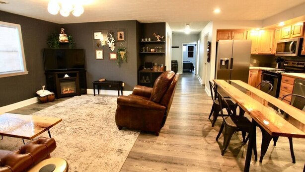 A spacious living room with a fireplace, leather sofa, and a dining area with a long wooden table and chairs. -  The Lounge - Downtown Chillicothe (Chillicothe)
