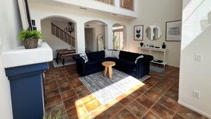 A spacious living area with a high ceiling, a staircase, and a balcony. - OCEANSIDE BEACH HOUSE~Dreamy Palm Tree Lined Street~5 MIN WALK to EVERYTHING!  (Oceanside)