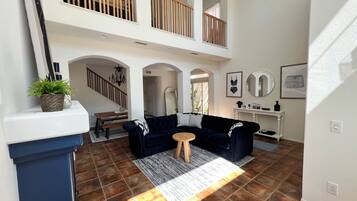 A spacious living area with a high ceiling, a staircase, and a balcony.