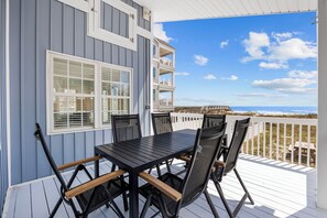 Terraza con mesa y sillas, con vista a la playa.