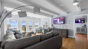 A modern living room with a grey sofa, two armchairs, and a TV mounted on the wall. - SY Oceanfront-Heated Pool-Bar-firepit-horseshoe (North Myrtle Beach)