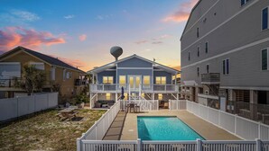 A residential property with a swimming pool, a covered patio, and a two-story building with a balcony. - SY Oceanfront-Heated Pool-Bar-firepit-horseshoe (North Myrtle Beach)