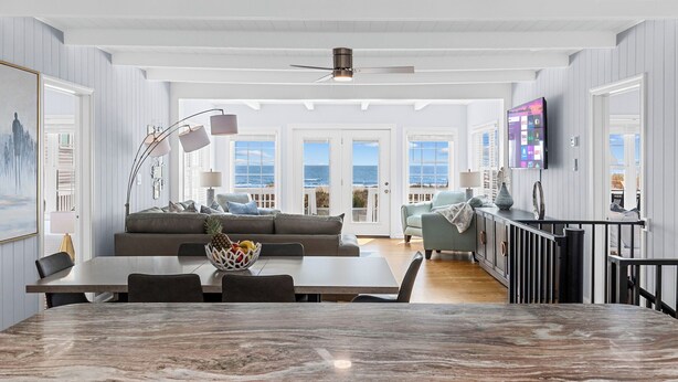 A spacious living area with a large dining table, a sofa, and a television. - SY Oceanfront-Heated Pool-Bar-firepit-horseshoe (North Myrtle Beach)
