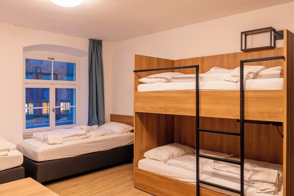 Quarto com beliches, janela com cortinas e vista para o exterior.