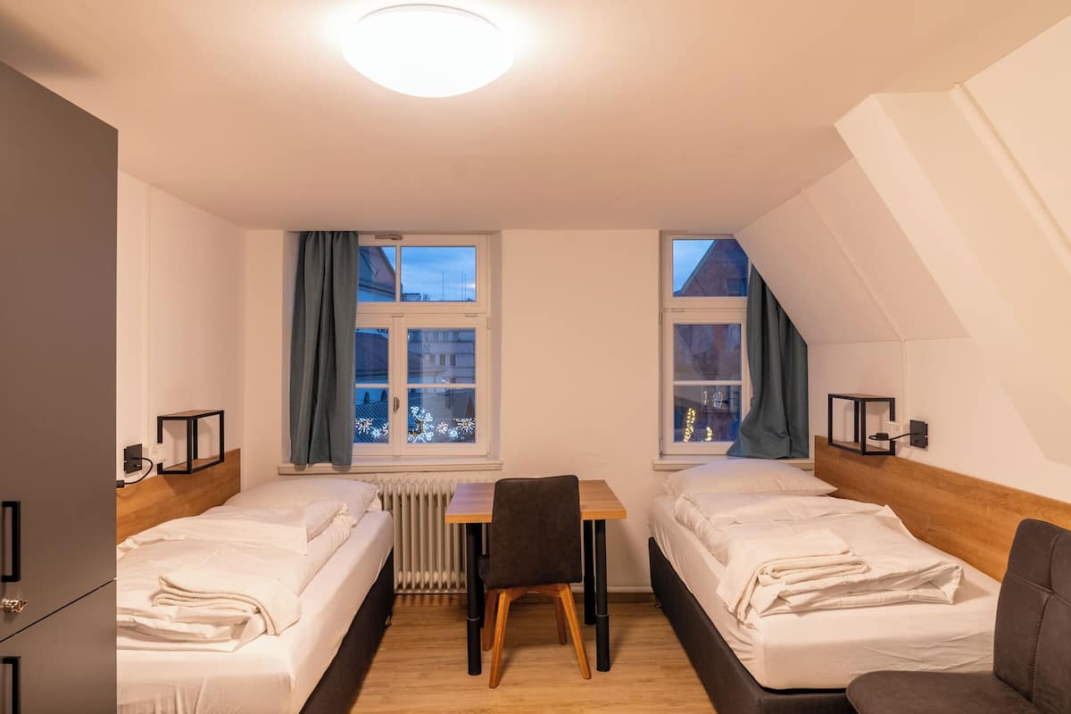 Hotellihuone, jossa on kaksi sänkyä, pöytä ja tuoli.