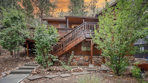 A wooden cabin with a stone foundation, a wooden staircase, and a stone pathway leading to the entrance. - Get Cozy on Rainbow, 1 Night Free! (Big Bear City)