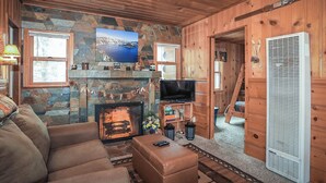 A cozy living room with a stone fireplace, a television, and a comfortable sofa. - Get Cozy on Rainbow, 1 Night Free! (Big Bear City)