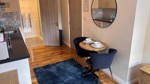 A compact kitchen with a sink, stove, and a dining area with a table and chairs. - Haven Homes (Luton)