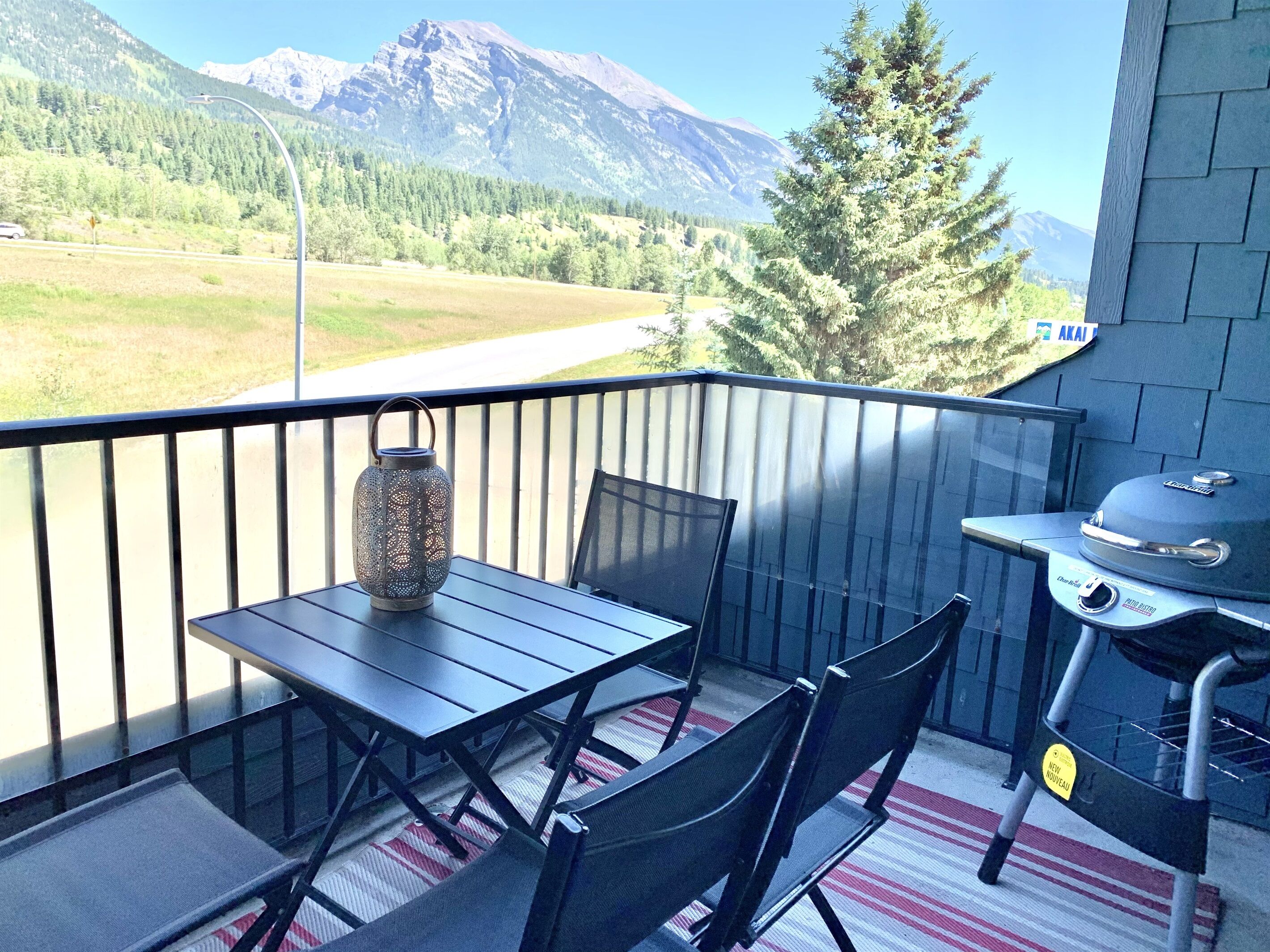Un balcone con tavolo e sedie, un lampione e un barbecue.