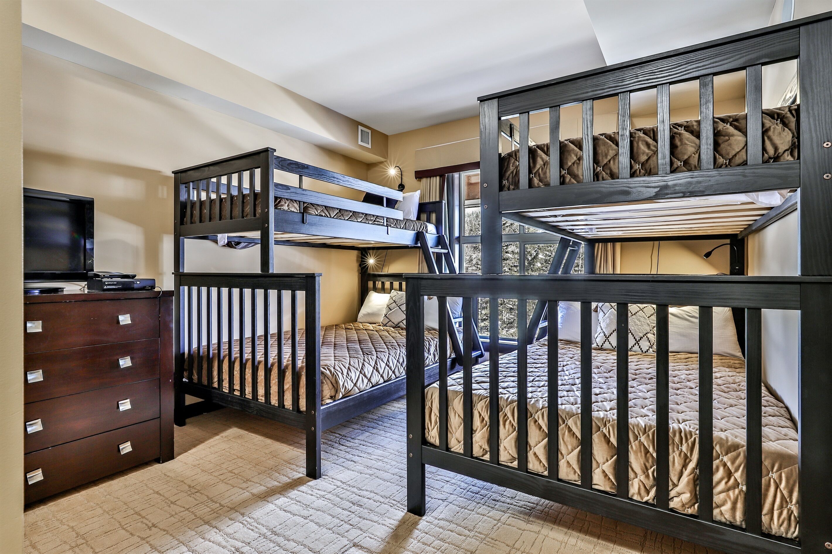 A room with bunk beds, a dresser, and a television.