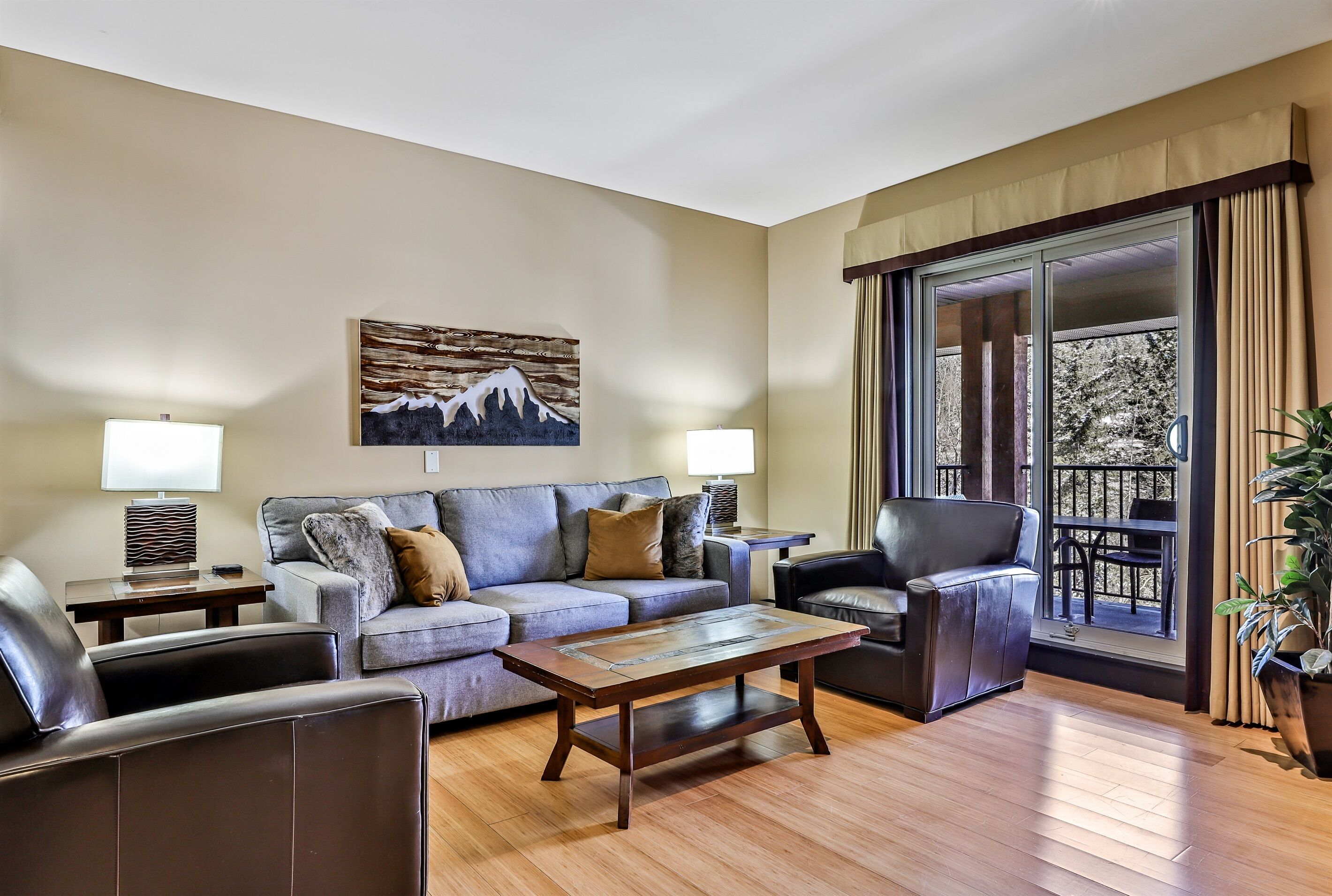 A living room with a sofa, armchairs, a coffee table, and a large window with curtains.