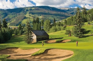 A golf course with bunkers, a wooden cabin, and a mountainous backdrop. - Charlie's Slopeside: Bachelor Gulch Ski-In/Out, Sleeps 8, Ritz Pool Access + Slopeside Hot Tubs (Avon)