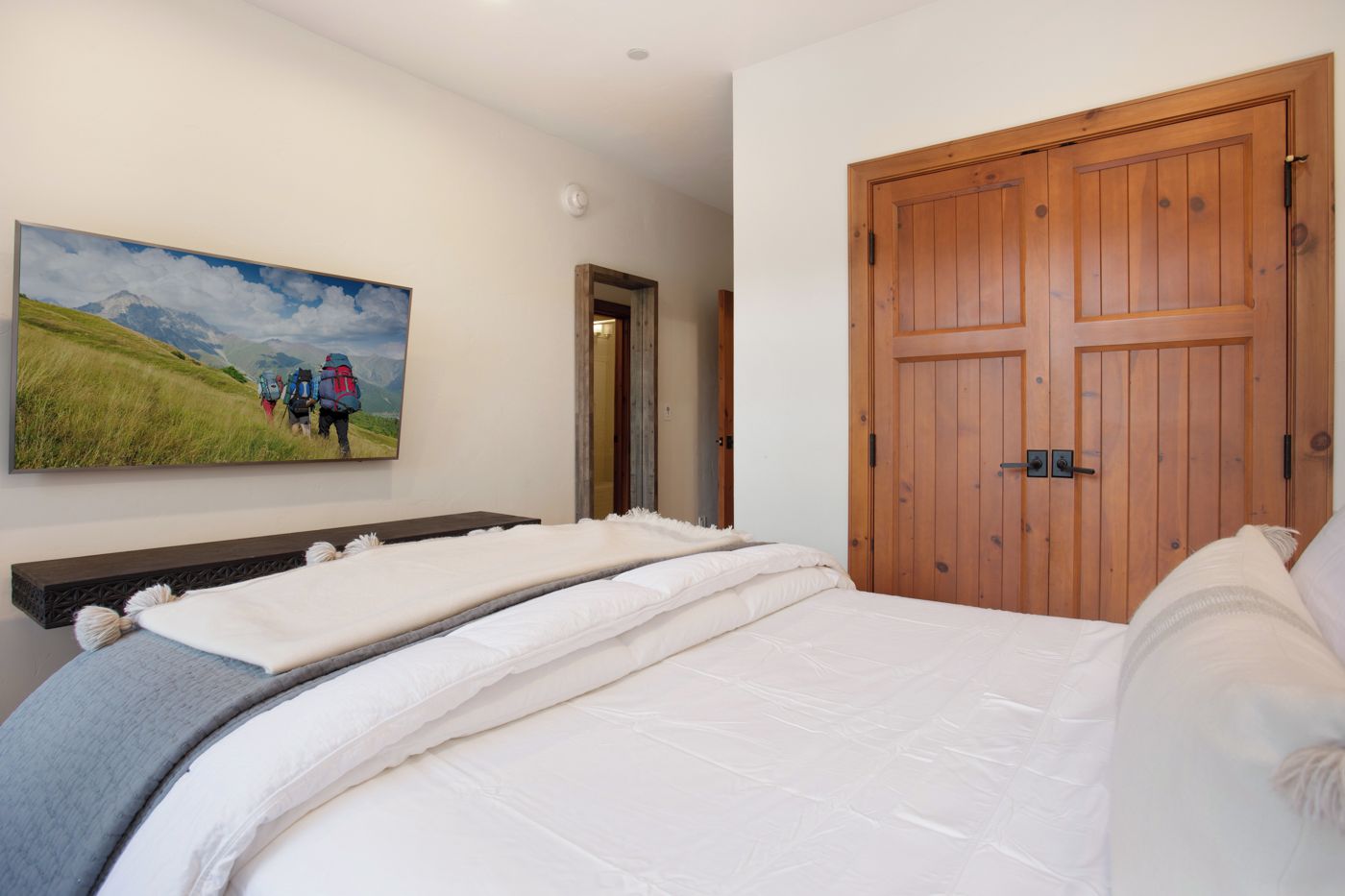 Ein Schlafzimmer mit einem großen Bett, einem Holzschrank und einem Gemälde von Wanderern in den Bergen.