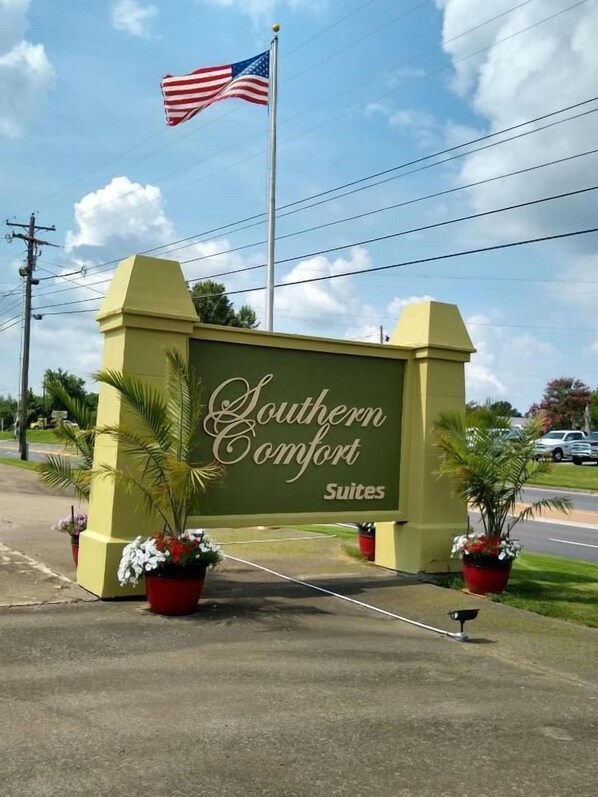 Un letrero de Southern Comfort Suites con una bandera al fondo.