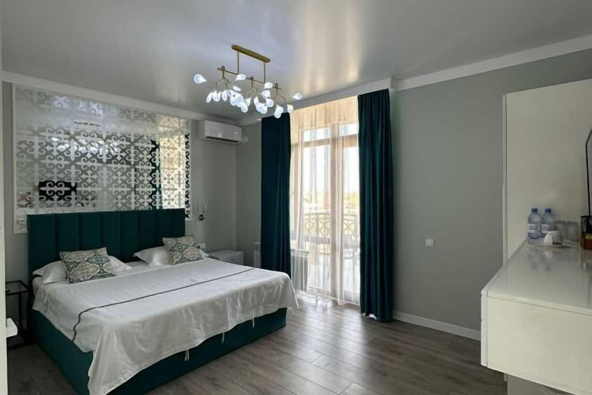A bedroom with a bed, a nightstand, a dresser, and a window with curtains.