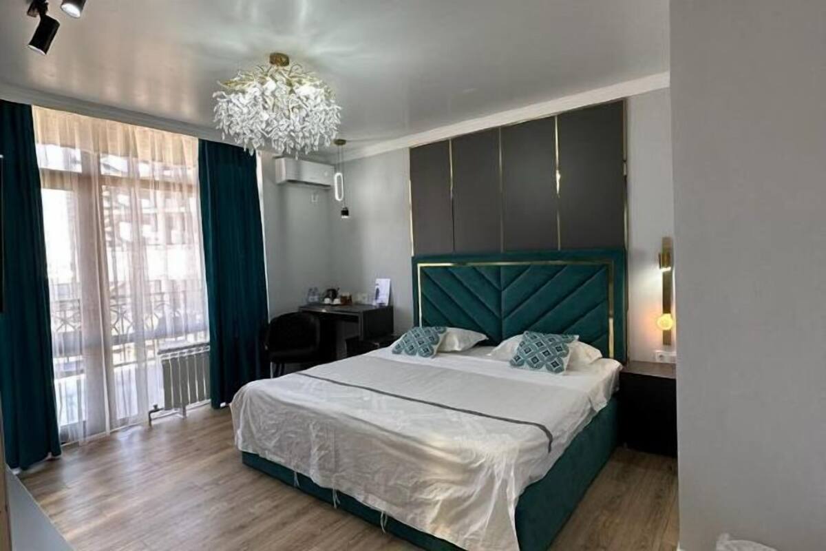 A hotel room with a large bed, a desk, and a chandelier.
