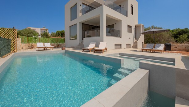 Une maison moderne à deux étages dotée d’une piscine, de chaises longues et d’un espace patio.