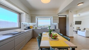 Une cuisine moderne avec une grande fenêtre, un coin repas doté d’une table jaune et un salon avec un canapé et un téléviseur.
