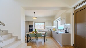 Une cuisine moderne avec un coin repas, un plancher en bois et un escalier menant à un autre niveau.