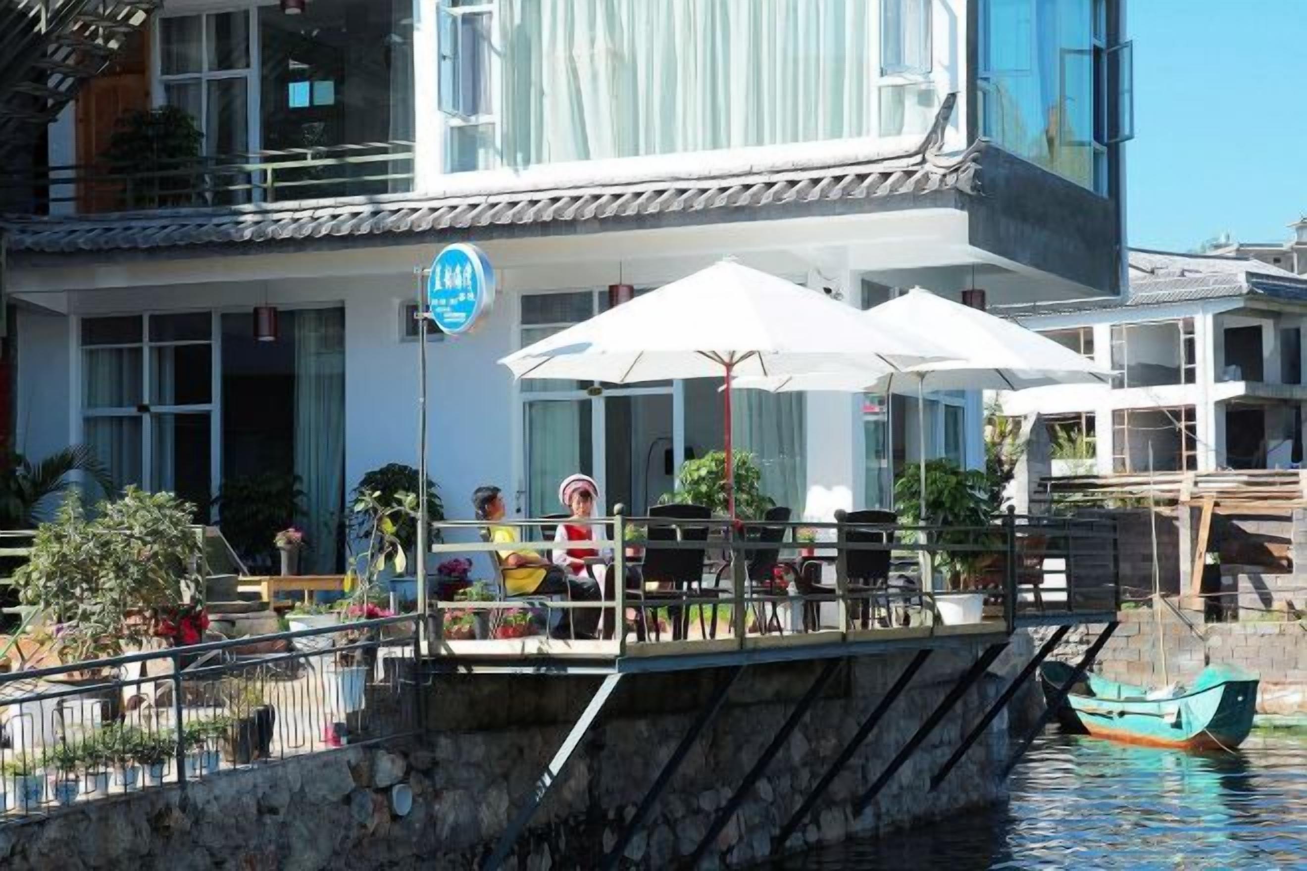 Una propiedad frente al mar con asientos al aire libre, un barco amarrado en el agua y un letrero que indica una calificación de 5 estrellas.