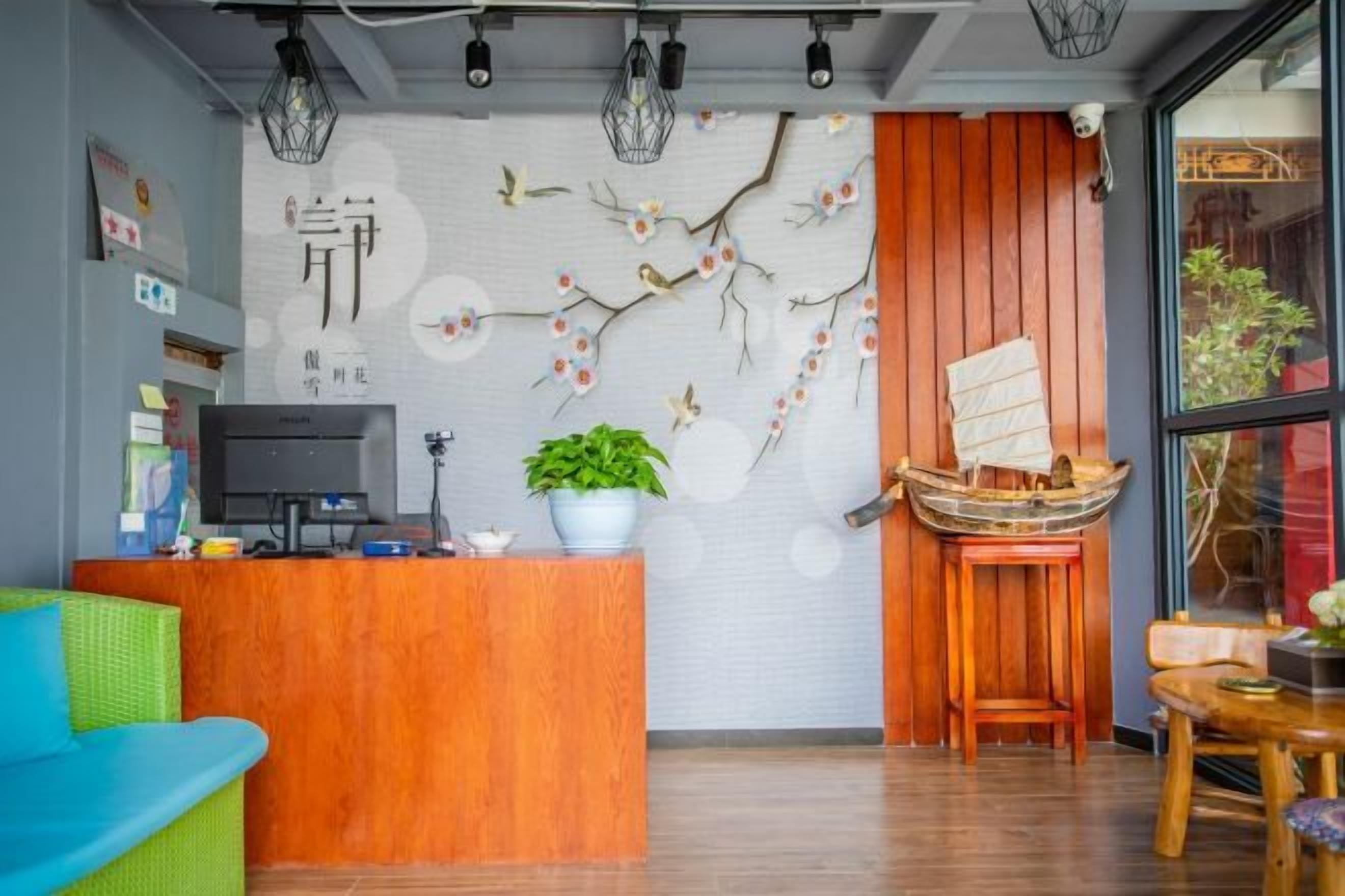 Un área de recepción con un escritorio de madera, una planta en maceta y un adorno en la pared.
