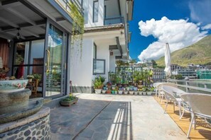 A balcony with potted plants, outdoor seating, and a view of the sea. - Lanyun Haiwan Inn (Dali City)