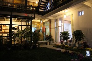 Une cour avec des plantes en pot et l’entrée d’un immeuble.