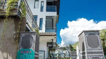 Un edificio de varios pisos con un balcón, un letrero verde y un cielo azul despejado.