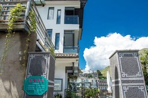 A multi-story building with a balcony, a green sign, and a clear blue sky. - Lanyun Haiwan Inn (Dali City)
