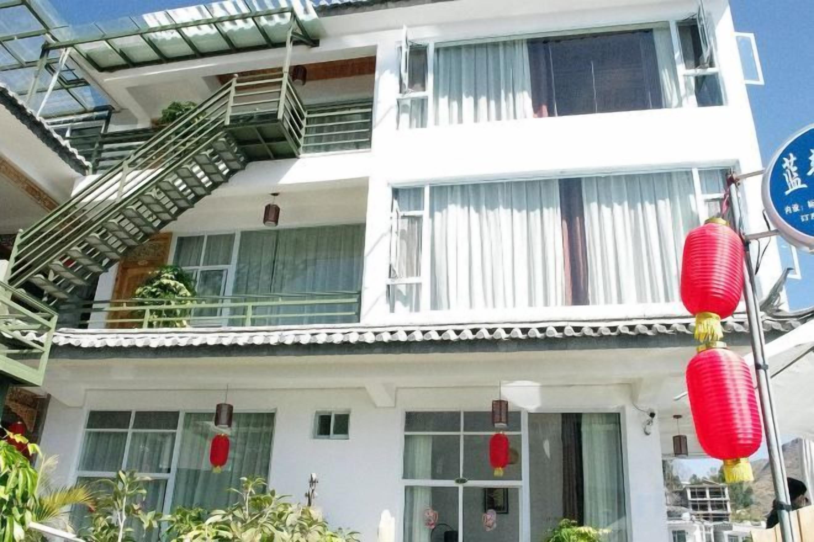 A multi-story building with a traditional architectural style, featuring a balcony with a metal railing and a staircase leading to an upper level.