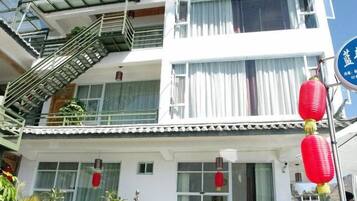 A multi-story building with a traditional architectural style, featuring a balcony with a metal railing and a staircase leading to an upper level.