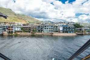 Un hôtel situé au bord de l’eau, composé de plusieurs bâtiments, avec une rivière et un paysage vallonné en arrière-plan.