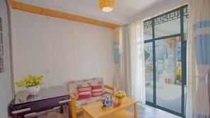 A living room with a sofa, a wooden coffee table, a small table with a vase and bottles, a lamp, and a sliding glass door leading outside. - Lanyun Haiwan Inn (Dali City)