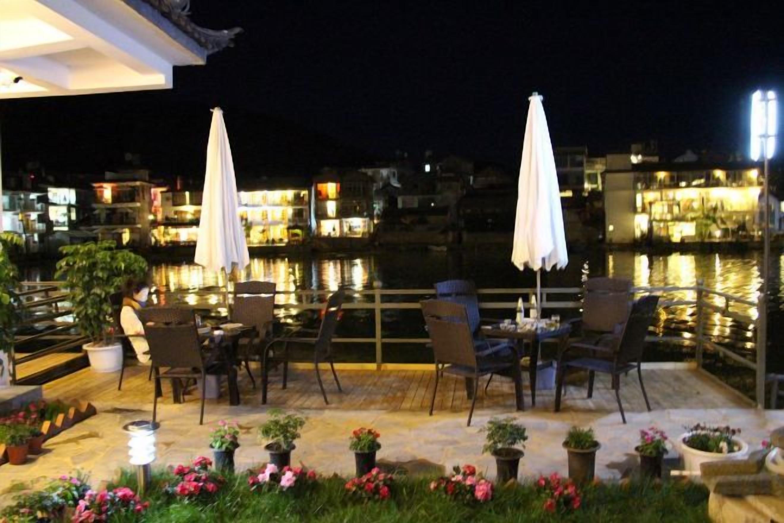 Terraza al aire libre con mesas, sillas, plantas en macetas y sombrillas.