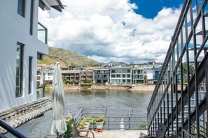 Un balcón con vistas a un río, edificios y un cielo nublado.