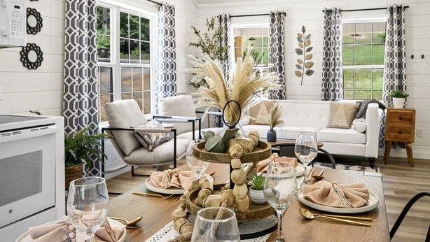 A dining area with a wooden table set for a meal, a sofa, and a kitchen in the background. - Newly Built Home in Pigeon Forge (Pigeon Forge)
