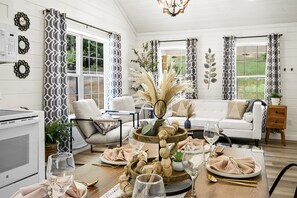 A dining area with a wooden table set for a meal, a sofa, and a kitchen in the background. - Newly Built Home in Pigeon Forge (Pigeon Forge)
