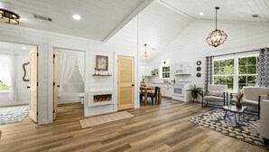 A spacious living room with a fireplace, wooden flooring, and a dining area with a table and chairs. - Newly Built Home in Pigeon Forge (Pigeon Forge)