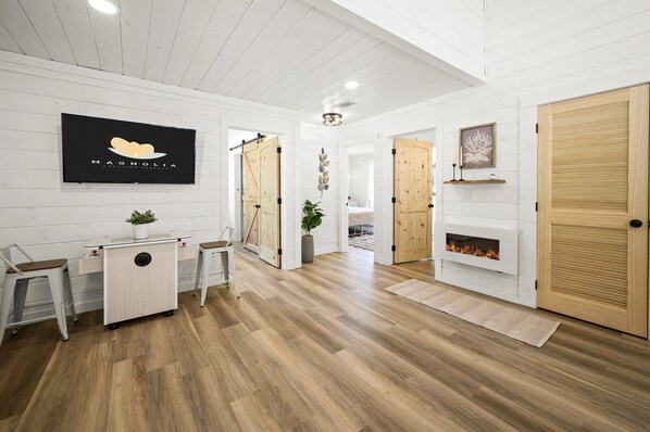 A modern interior with wooden floors, a reception desk, a fireplace, and a television displaying a logo. - Newly Built Home in Pigeon Forge (Pigeon Forge)