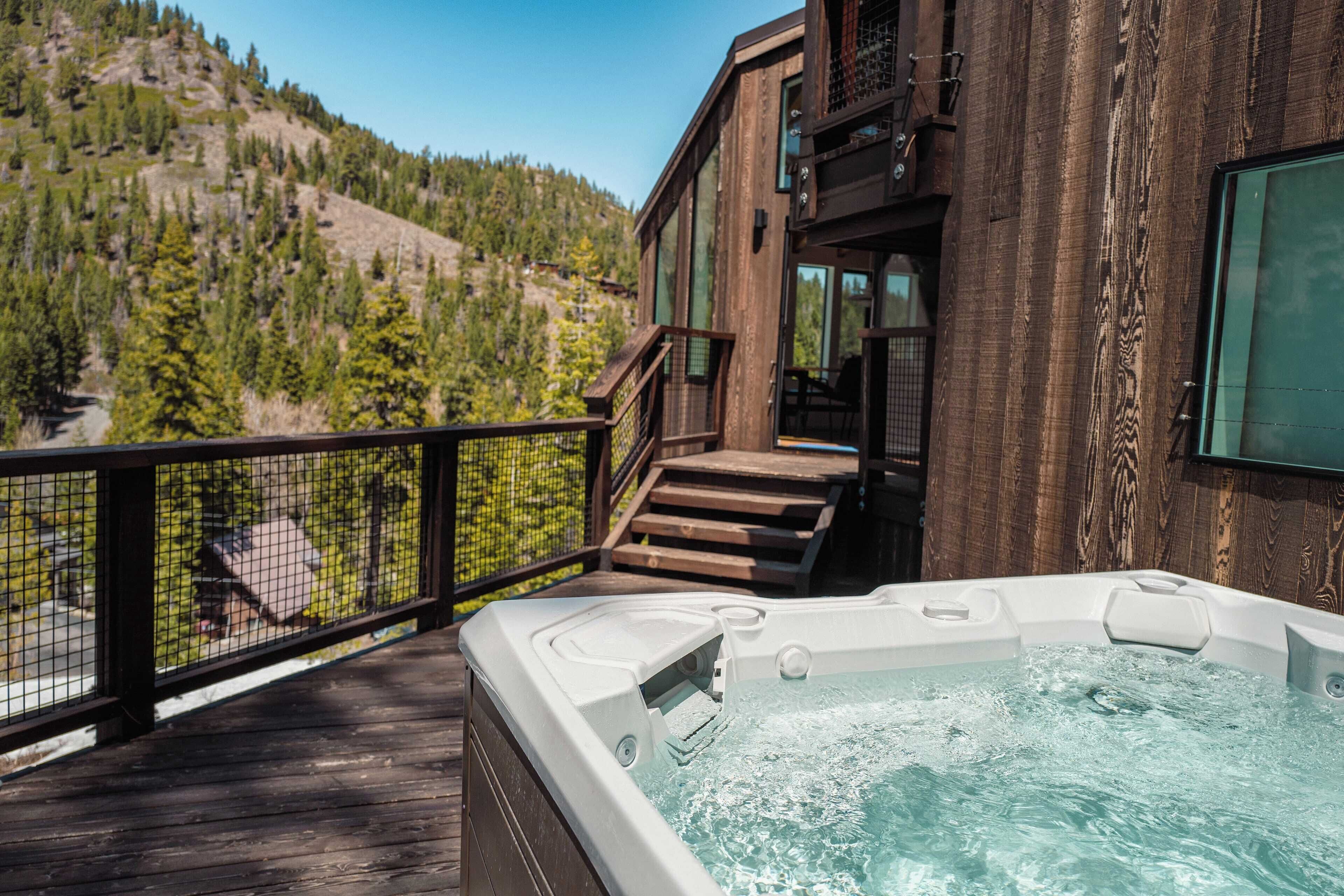 A hot tub on a wooden deck with a view of a mountainous landscape.