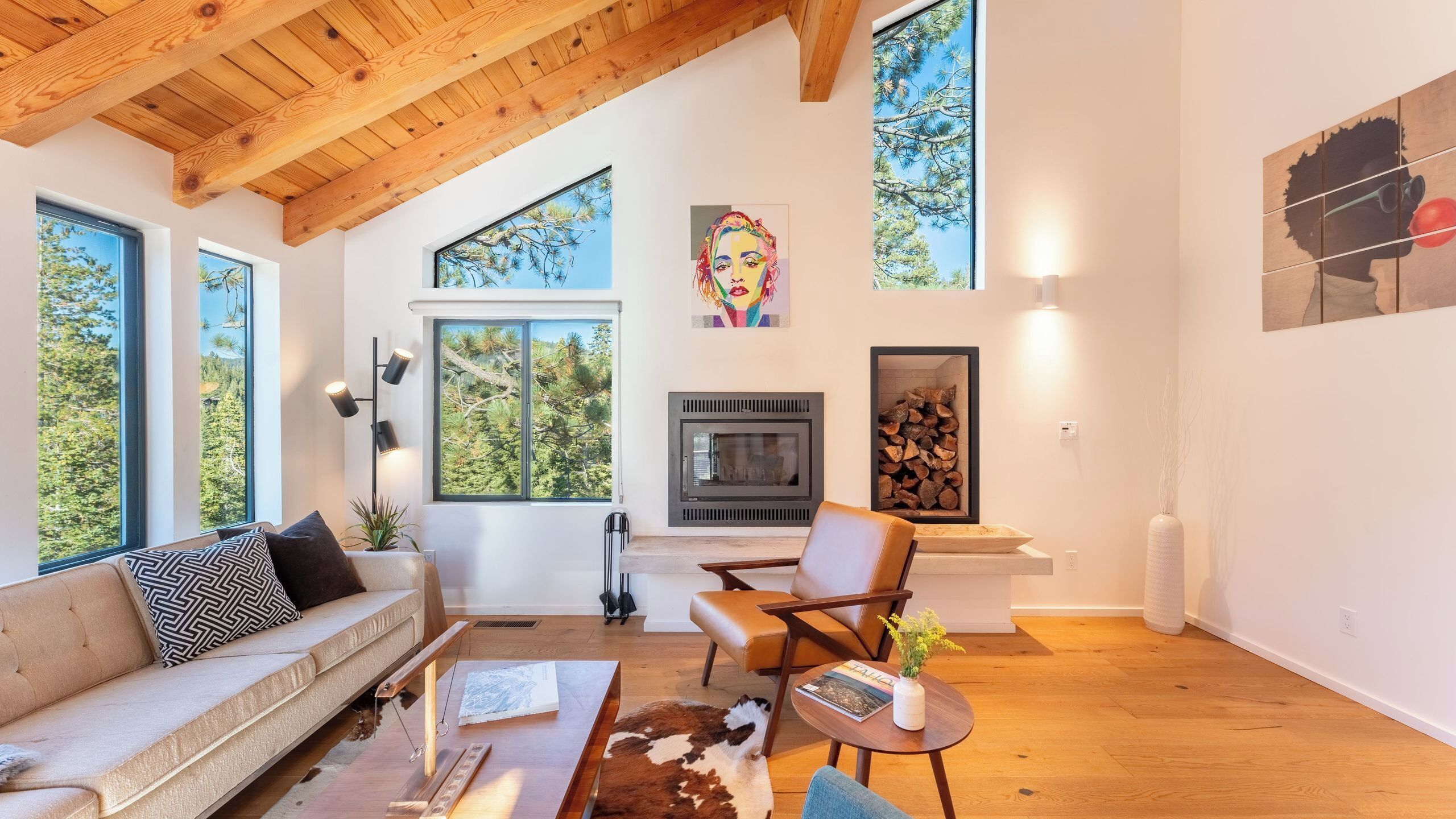 Uma sala de estar moderna com lareira, janelas amplas, um sofá e um espaço de jantar.